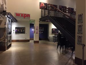 Lower level lobby of World Cafe Live. There are stairs to the right, and underneath them on the back wall of the lobby are the restrooms.